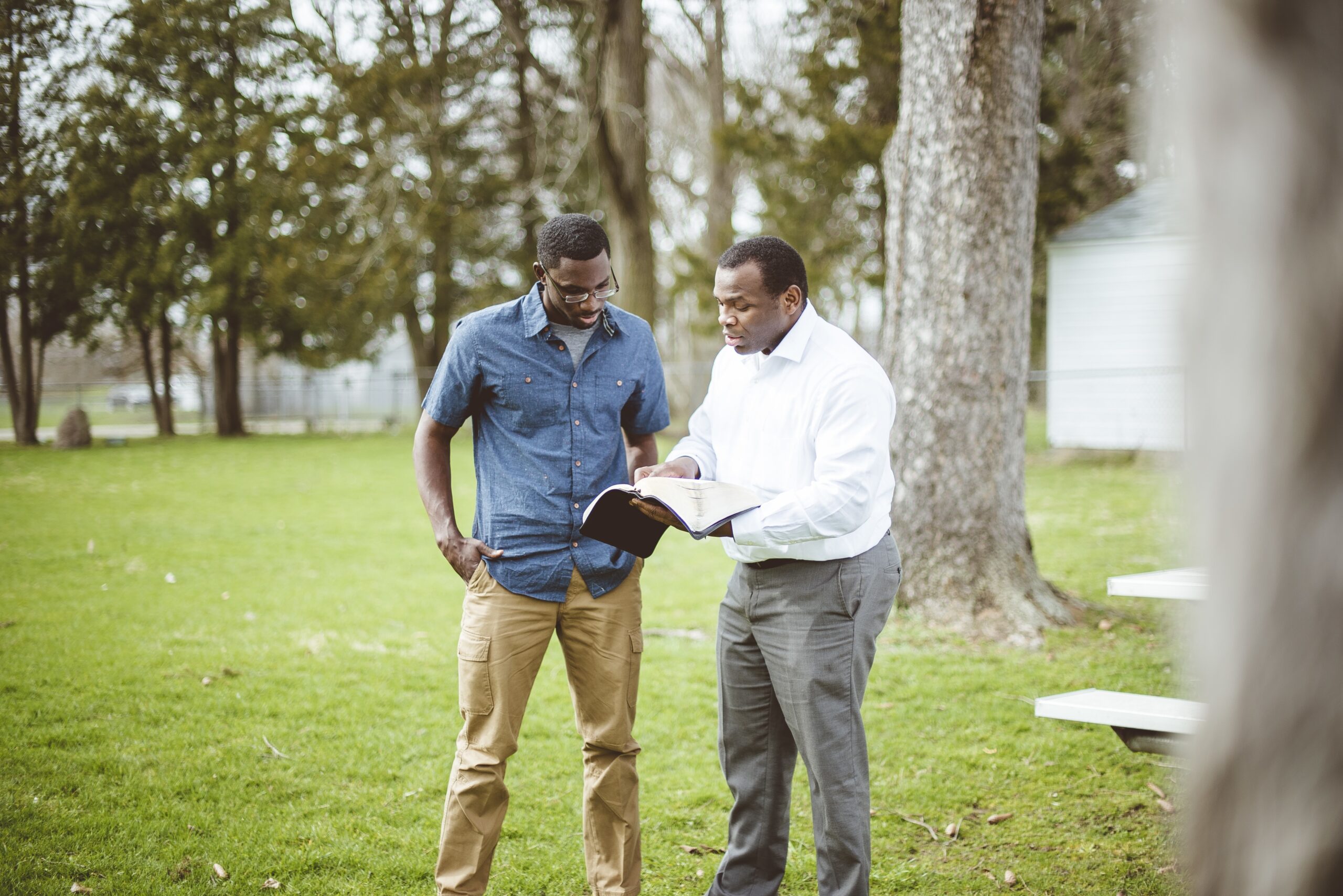 Two African-American male friends standing at the park and discussing the Bible